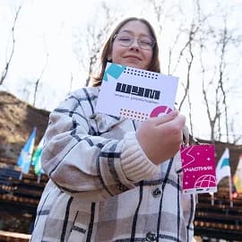 Участница Центра «ШУМ» держит карточку с логотипом